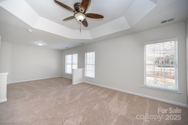 carpeted spare room with ceiling fan and a tray ceiling