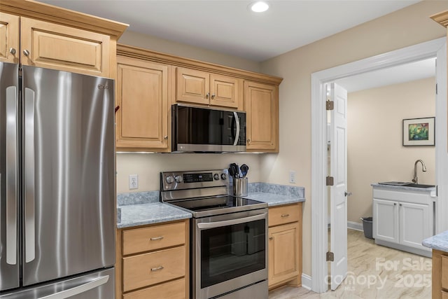 kitchen with stainless steel appliances, light stone countertops, sink, and light brown cabinetry