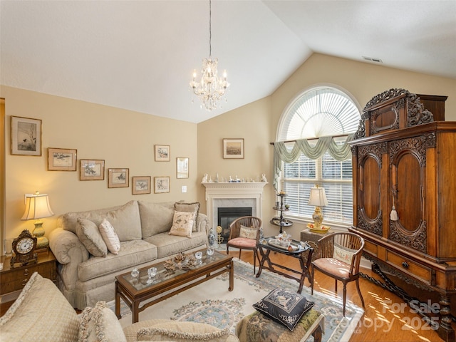 living room with hardwood / wood-style flooring, lofted ceiling, and a notable chandelier