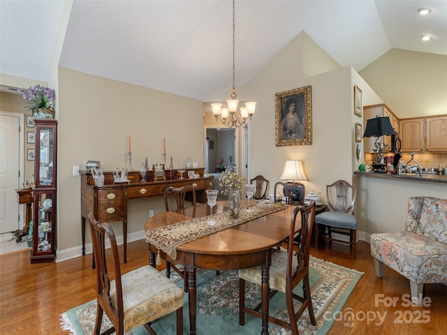 dining room featuring a notable chandelier, high vaulted ceiling, and light hardwood / wood-style flooring