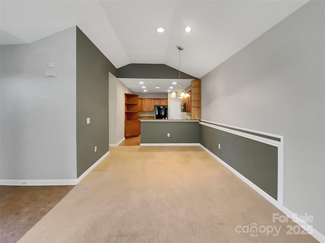 unfurnished living room with lofted ceiling, light carpet, and an inviting chandelier