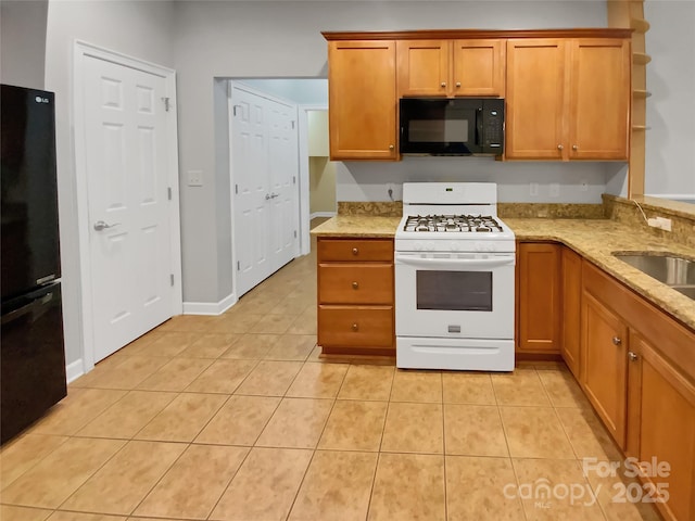 kitchen with light tile patterned flooring, light stone countertops, sink, and black appliances