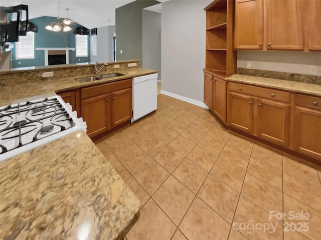 kitchen with sink, light tile patterned floors, dishwasher, light stone countertops, and decorative light fixtures