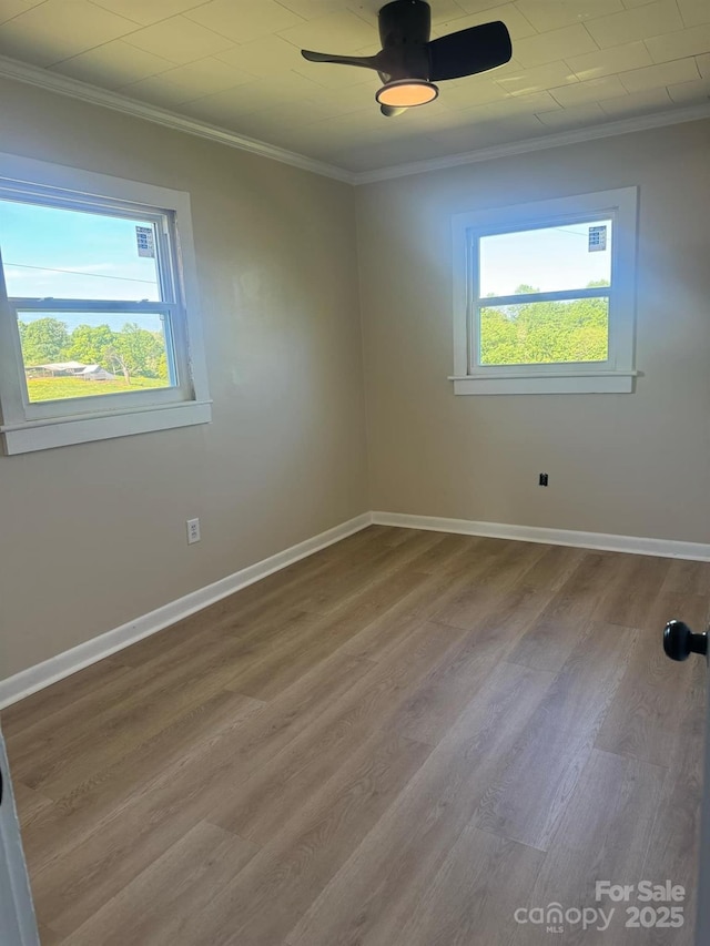 spare room with hardwood / wood-style flooring, ornamental molding, a healthy amount of sunlight, and ceiling fan