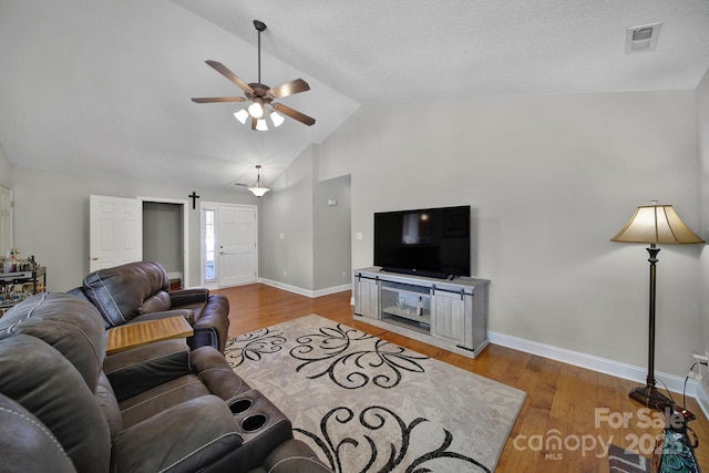 living area with ceiling fan, a textured ceiling, wood finished floors, visible vents, and baseboards