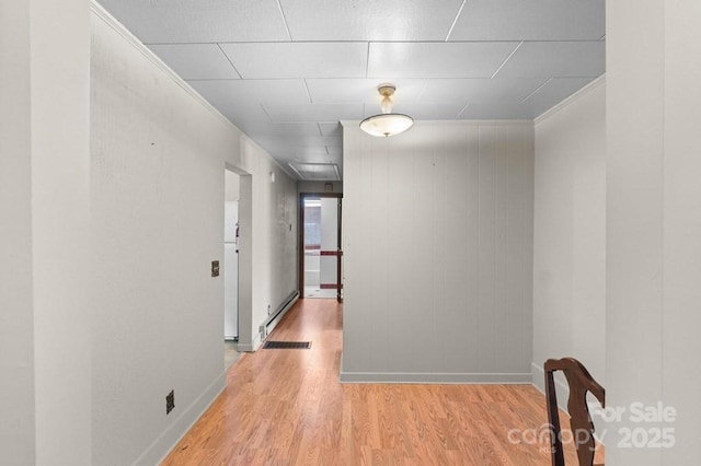 hallway with crown molding, a baseboard heating unit, and light hardwood / wood-style flooring