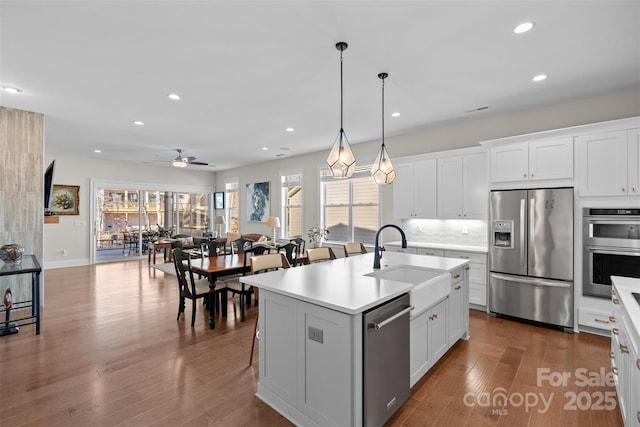 kitchen with a kitchen island with sink, sink, stainless steel appliances, and white cabinets