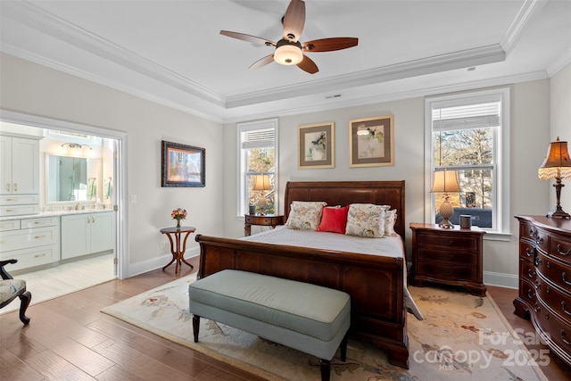 bedroom with crown molding, a raised ceiling, sink, and light hardwood / wood-style flooring