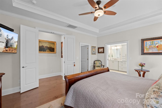 bedroom featuring hardwood / wood-style flooring, crown molding, ceiling fan, and a tray ceiling