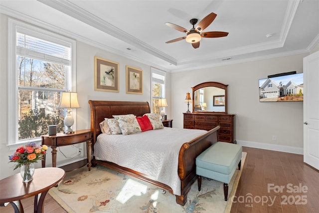 bedroom with crown molding, ceiling fan, wood-type flooring, and a tray ceiling