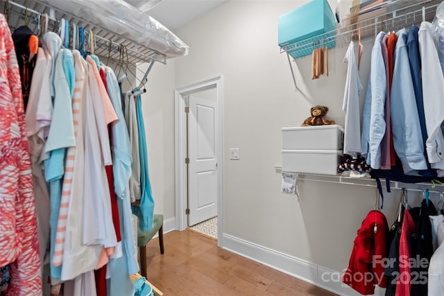 walk in closet with light hardwood / wood-style flooring