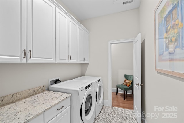 clothes washing area featuring cabinets and independent washer and dryer