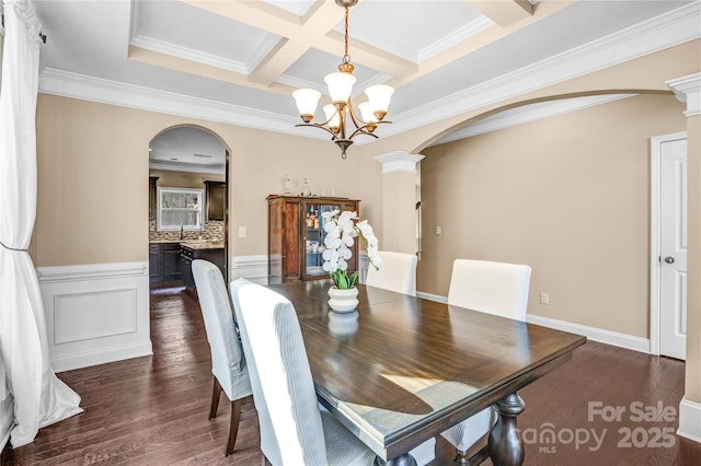 dining space featuring ornate columns, dark hardwood / wood-style floors, beamed ceiling, a chandelier, and coffered ceiling