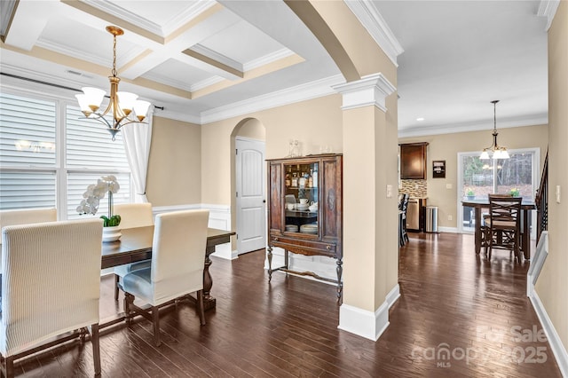 dining area with an inviting chandelier, dark hardwood / wood-style flooring, and decorative columns