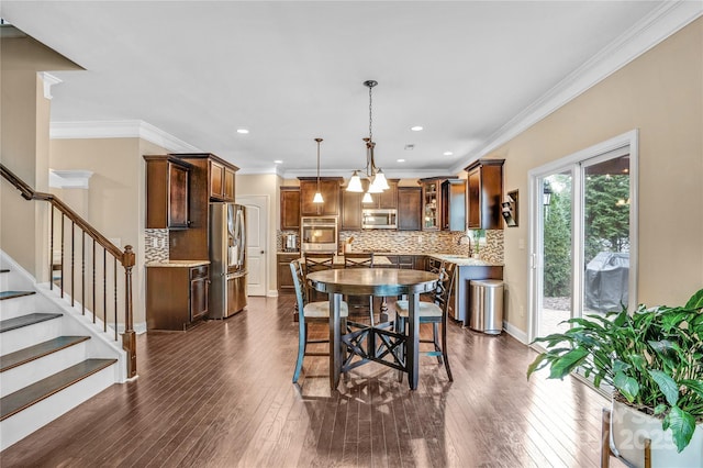 dining area featuring ornamental molding, dark wood-type flooring, and sink