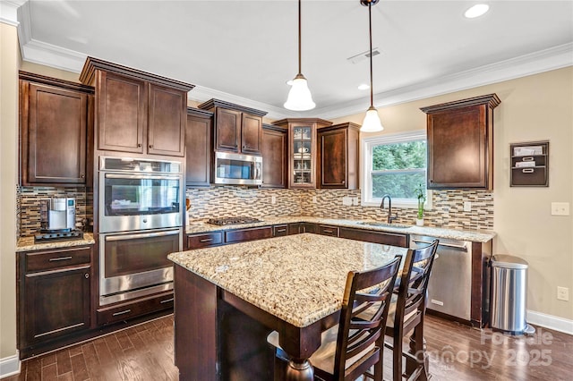 kitchen with pendant lighting, sink, appliances with stainless steel finishes, dark hardwood / wood-style floors, and dark brown cabinetry