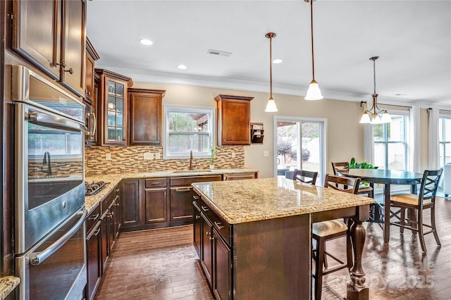 kitchen featuring pendant lighting, sink, a breakfast bar, double oven, and a kitchen island