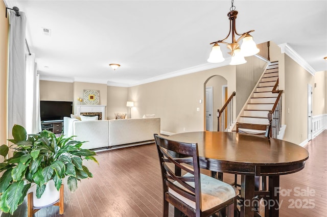 dining space with ornamental molding, dark wood-type flooring, and a notable chandelier