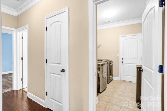 clothes washing area featuring light hardwood / wood-style floors, ornamental molding, and washer and dryer