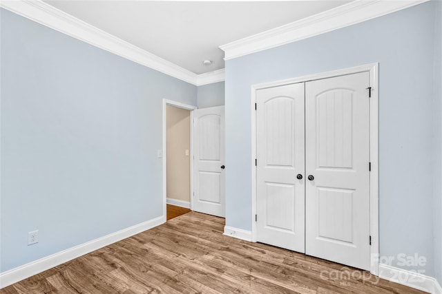 unfurnished bedroom featuring wood-type flooring, crown molding, and a closet