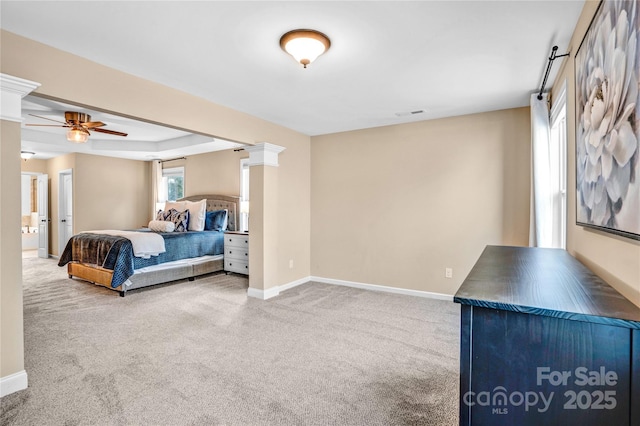 carpeted bedroom featuring a raised ceiling and ornate columns