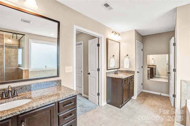 bathroom with tile patterned floors, vanity, and a tile shower