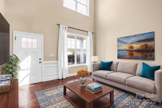 living room with dark wood-type flooring and a high ceiling