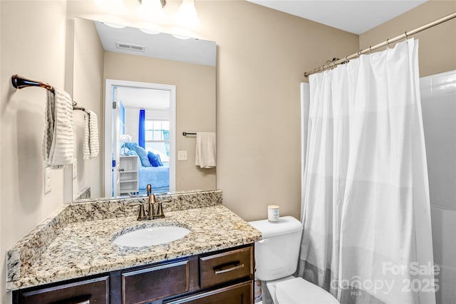 bathroom featuring vanity, walk in shower, and toilet