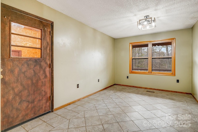 unfurnished room featuring visible vents, a textured ceiling, baseboards, and light tile patterned floors