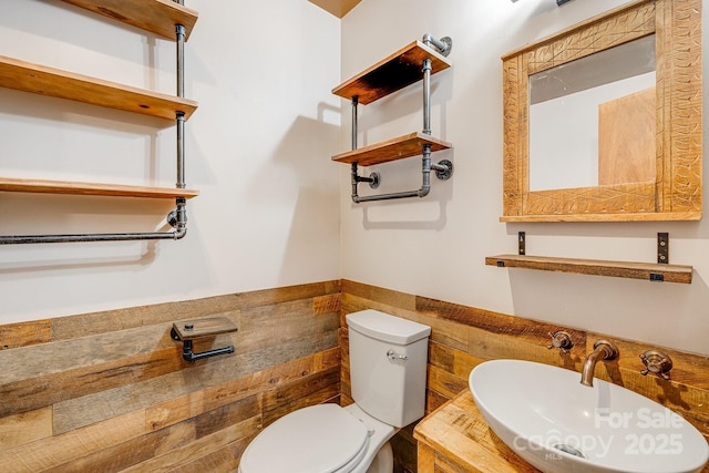 bathroom with wainscoting, a sink, and toilet