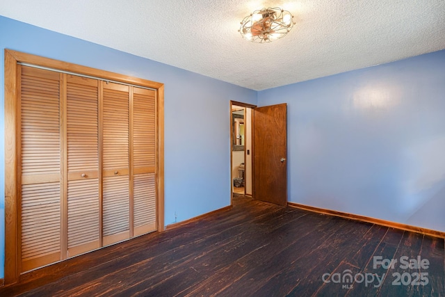 unfurnished bedroom featuring a closet, a textured ceiling, baseboards, and hardwood / wood-style floors