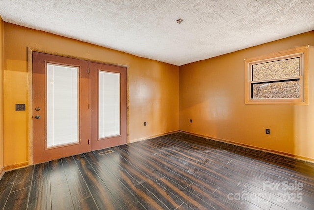 empty room featuring a textured ceiling, baseboards, and wood finished floors