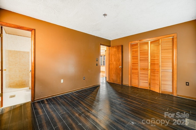 unfurnished bedroom with a textured ceiling, a closet, wood finished floors, and baseboards