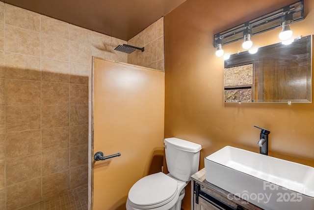 full bathroom featuring toilet, tiled shower, and vanity