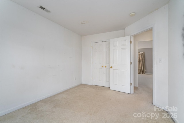 unfurnished bedroom featuring light carpet and a closet