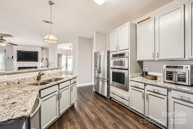 kitchen featuring dark wood-type flooring, sink, white cabinetry, hanging light fixtures, and stainless steel appliances