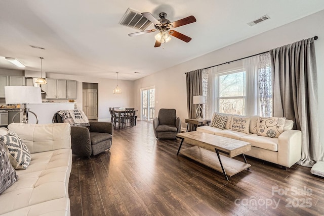 living room with plenty of natural light, dark wood-type flooring, and ceiling fan