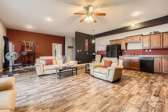 living room with light hardwood / wood-style flooring, wet bar, and ceiling fan