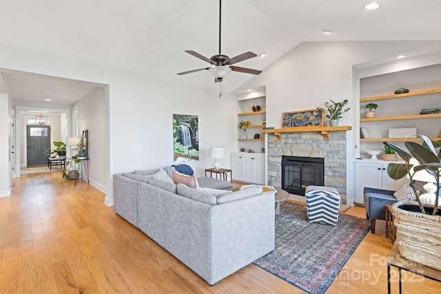 living room with lofted ceiling, a fireplace, light hardwood / wood-style floors, and built in features