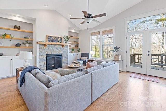 living room with lofted ceiling, built in features, a fireplace, and light hardwood / wood-style flooring