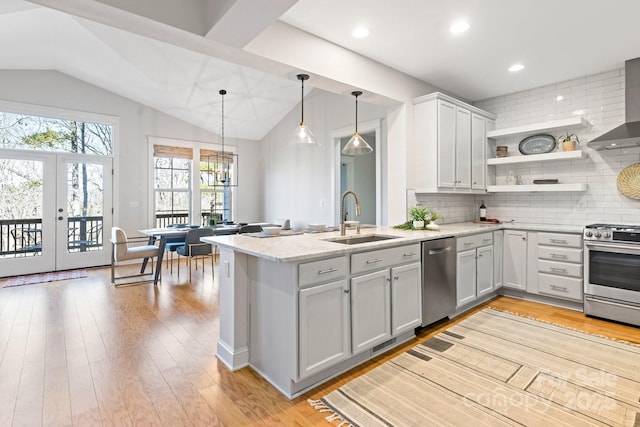 kitchen with sink, decorative light fixtures, appliances with stainless steel finishes, kitchen peninsula, and light stone countertops