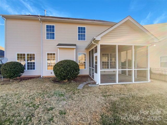 rear view of house featuring a sunroom and a lawn