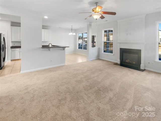 unfurnished living room with ceiling fan and light carpet