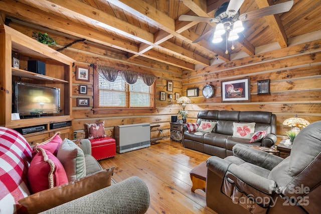 living room with beamed ceiling, ceiling fan, wooden walls, and light wood-type flooring