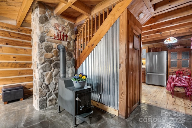 interior space with a wood stove, hardwood / wood-style floors, and stainless steel fridge