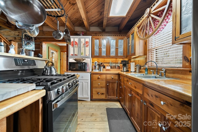 kitchen with sink, stainless steel gas range oven, light hardwood / wood-style flooring, wooden ceiling, and beam ceiling