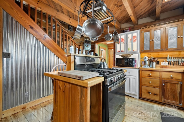 kitchen featuring butcher block counters, beam ceiling, stainless steel gas range, and light hardwood / wood-style floors