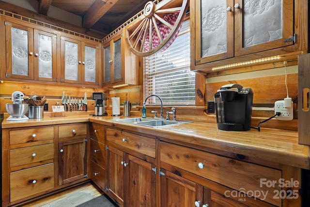 kitchen featuring beamed ceiling, light hardwood / wood-style floors, and sink