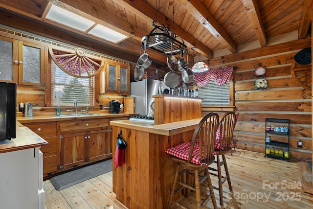 kitchen with a kitchen island, sink, stainless steel fridge, wood ceiling, and light wood-type flooring