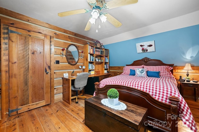 bedroom featuring light hardwood / wood-style flooring and wooden walls